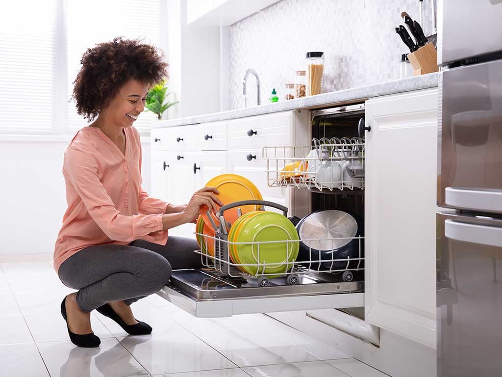 Woman kneeling to load dishwasher