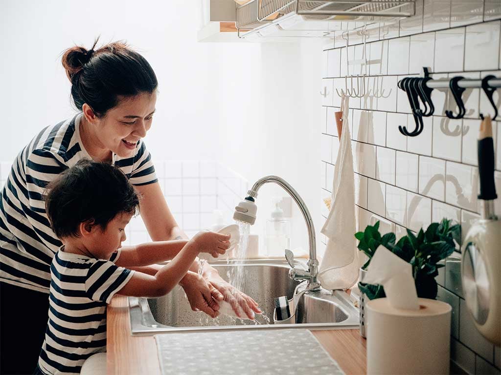Mom and boy playing with water spout at kitchen sink