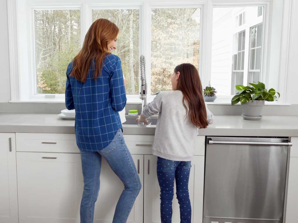 A-happy-mother-and-daughter-hanging-by-the-kitchen-sink